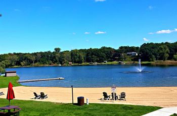 a sandy beach in front of a lake with a fountain